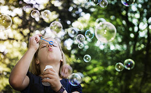 Bild vergrern: Little girl blowing bubbles.